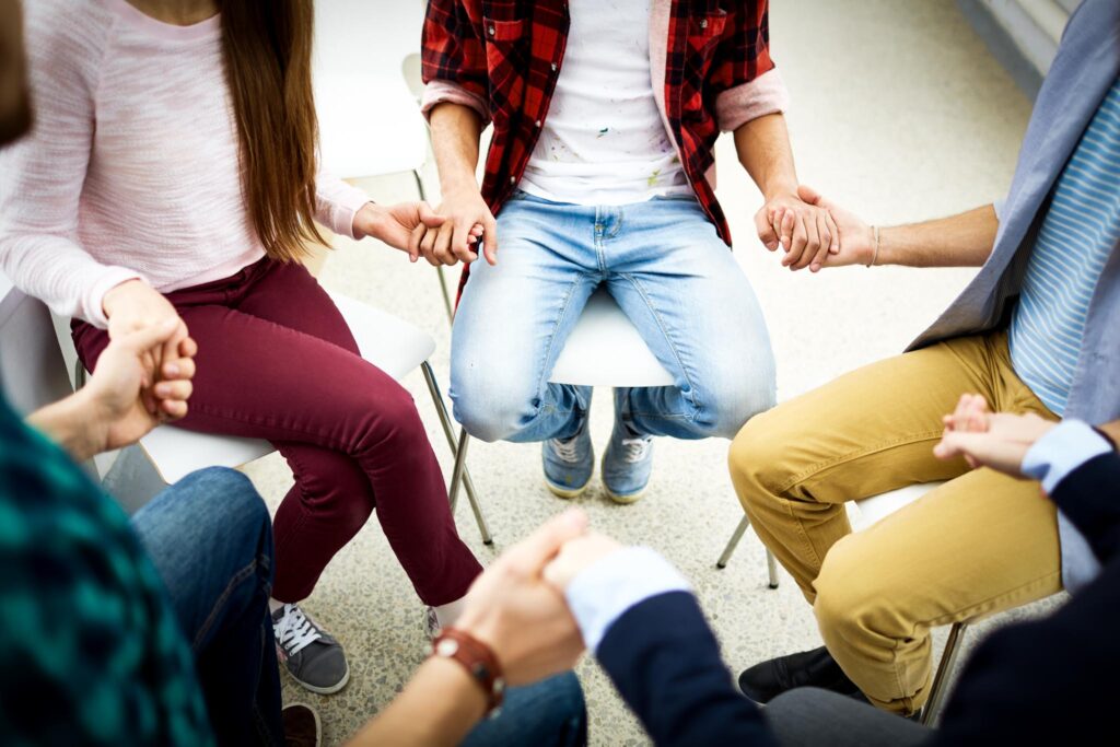 Young people holding by hands at psychological therapy course